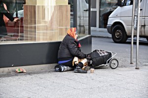 Homeless women sitting alone on a city sidewalk